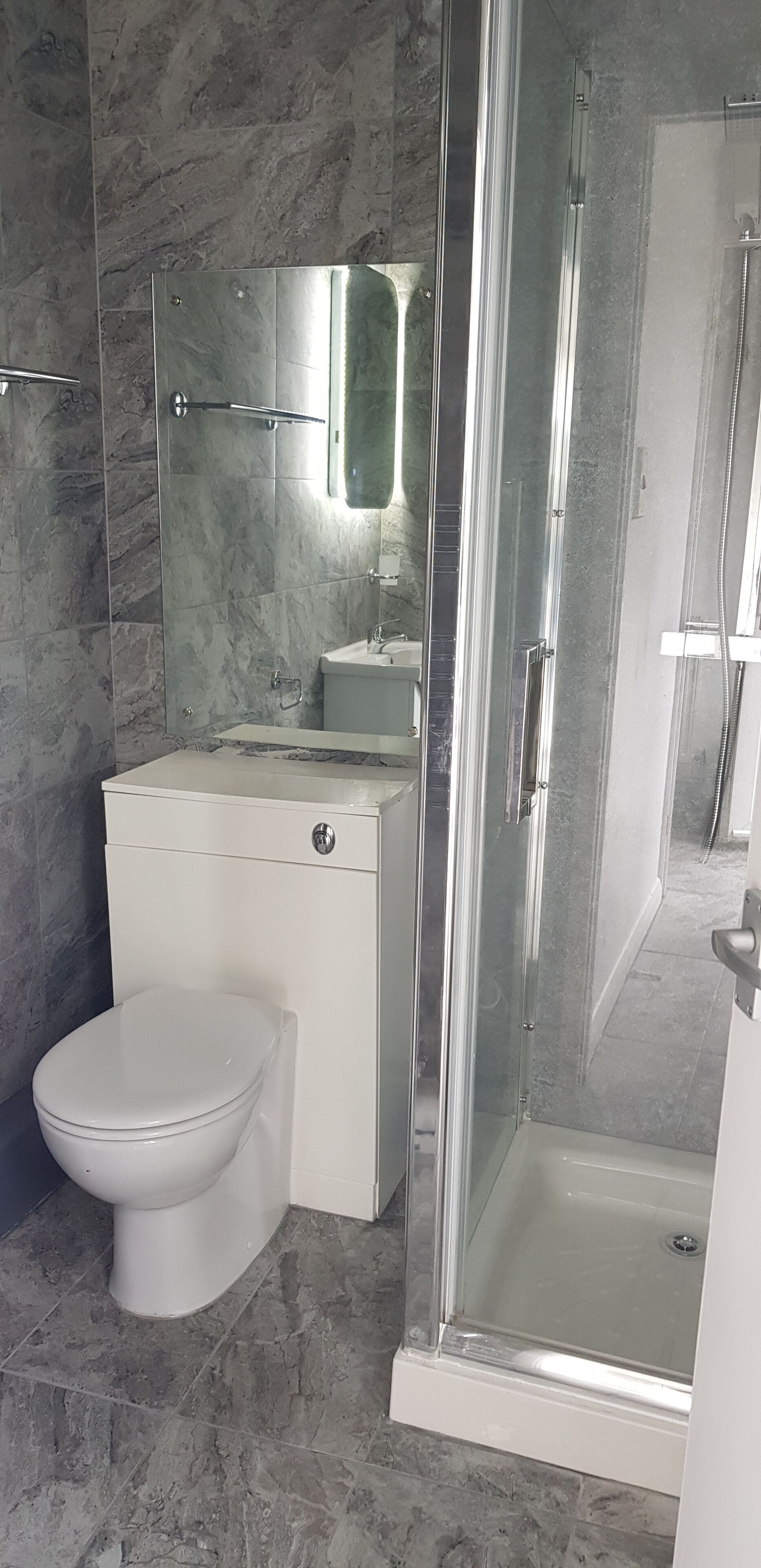 A bathroom with a toilet, a sink, and a glass-enclosed shower area.