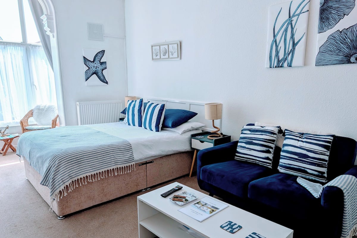 A modern bedroom with a bed, a sofa, a coffee table, and a chair.