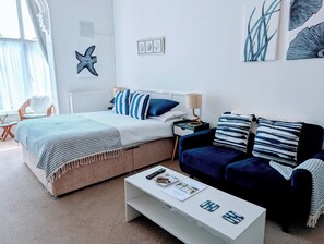 A modern bedroom with a bed, a sofa, a coffee table, and a chair.