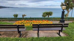 A park bench overlooking a flower bed and a body of water.