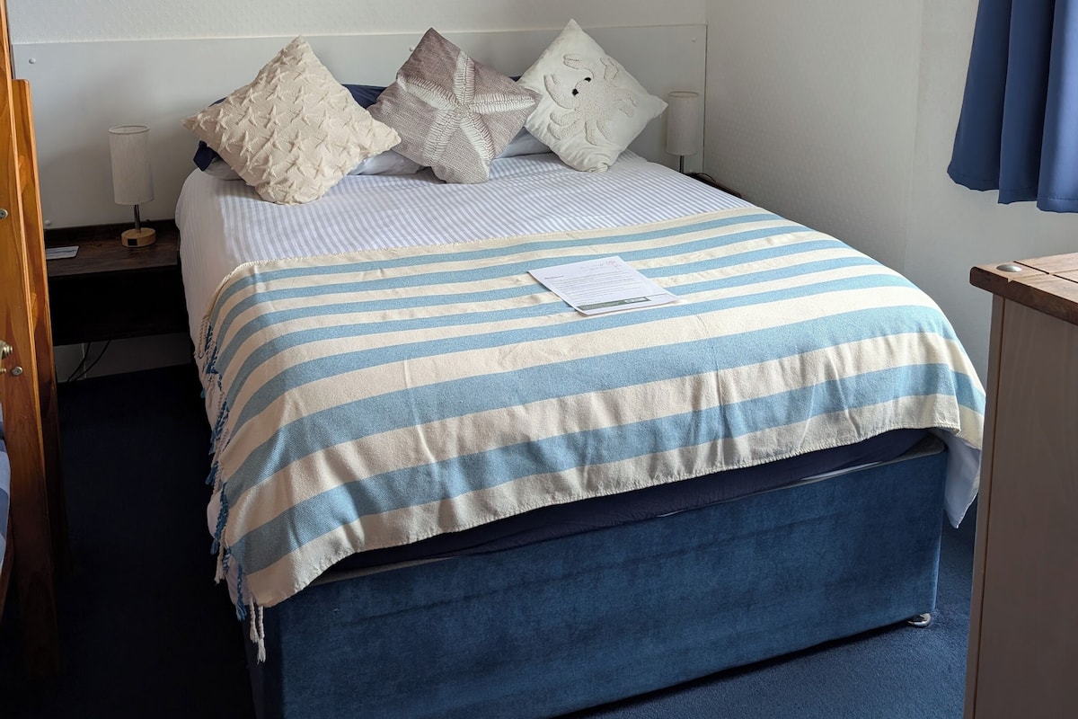 A bedroom with a bed, striped bedding, and two wall art pieces.