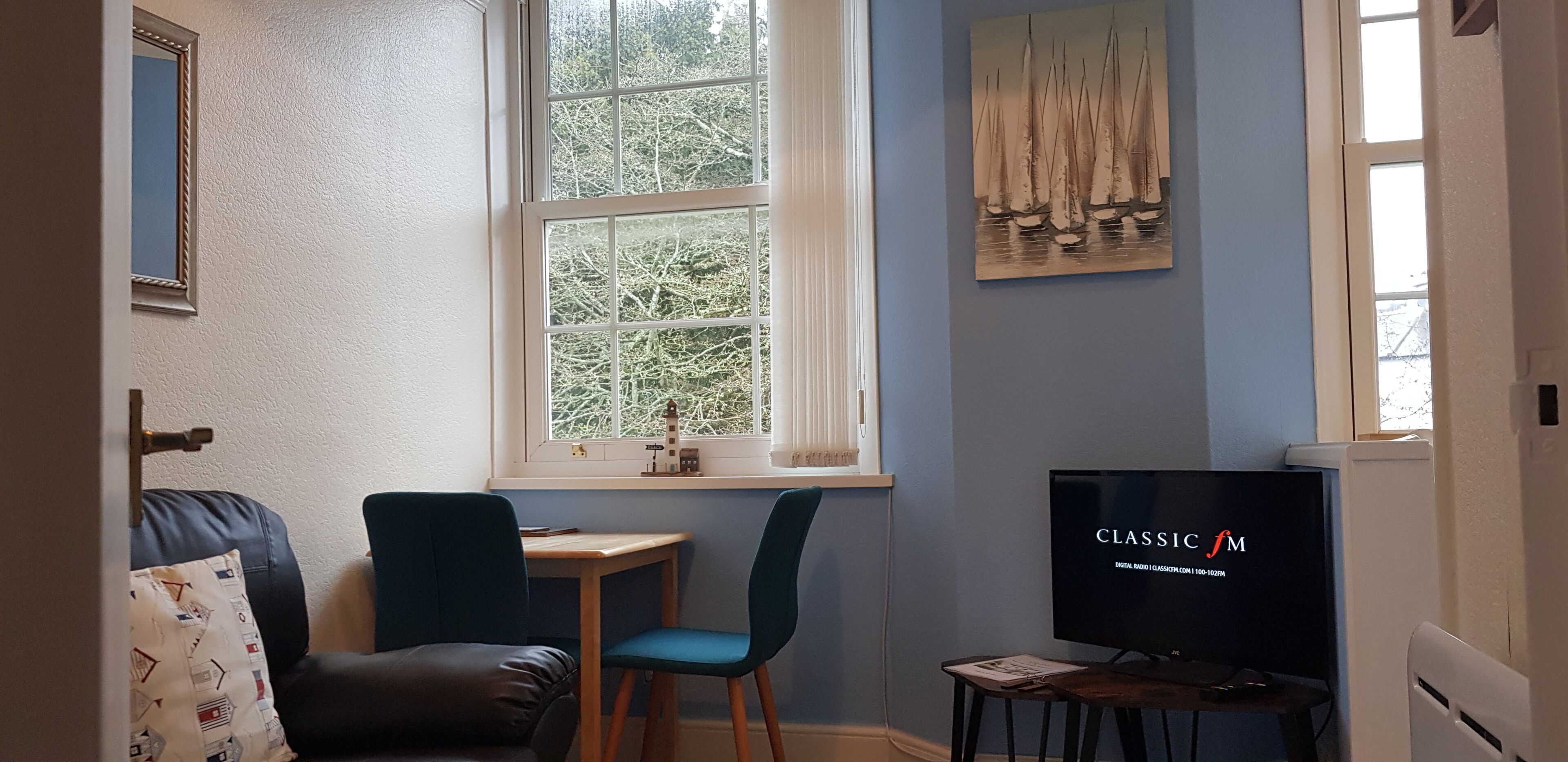 Una habitación con ventana, televisión, escritorio y silla.