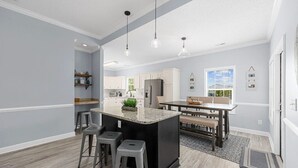 A modern kitchen with a central island, bar stools, and pendant lighting. - Pet-friendly Home w/ Pool, Hot Tub and Golf Cart (North Myrtle Beach)