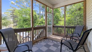 A covered porch with wooden railings, two chairs, and a ceiling fan. - Pet-friendly Home w/ Pool, Hot Tub and Golf Cart (North Myrtle Beach)