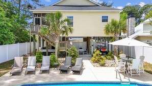 A two-story house with a swimming pool, outdoor seating, and a covered patio area. - Pet-friendly Home w/ Pool, Hot Tub and Golf Cart (North Myrtle Beach)