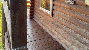 Een houten vakantiehuis met een veranda, een raam en een bord met een welkomstboodschap.