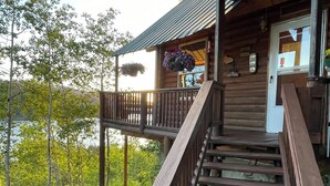 Een houten chalet met een houten trap naar een veranda met bloembakken.