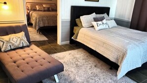 A bedroom with a large bed, a smaller bed, a sofa, and a nightstand. - Misty Morn Suite in Cascade Inn at Fall Creek Falls (Pikeville)