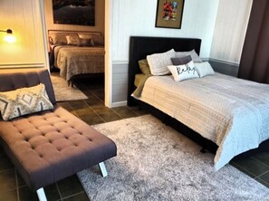 Restful retreat with a large bed, tufted ottoman, and decorative rug.
