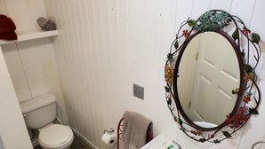 A bathroom with a toilet, sink, and a decorative mirror. - Misty Morn Suite in Cascade Inn at Fall Creek Falls (Pikeville)