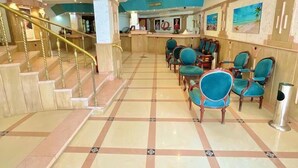 A hotel lobby with a tiled floor, a reception desk, a staircase, and several chairs. - Diana Hotel  (Hurghada)