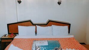 A neatly made bed with an orange patterned bedspread, white pillows, and a decorative box on the bed. - Diana Hotel  (Hurghada)
