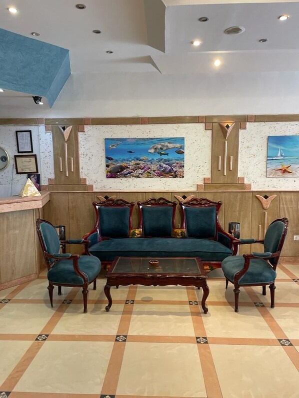 A room with a sofa set, chairs, a coffee table, and a wall with framed pictures. - Diana Hotel (Hurghada)