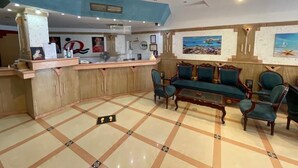 A lobby with a reception desk, seating area, and artwork on the walls. - Diana Hotel  (Hurghada)