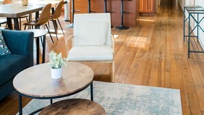 A spacious living area with a dining table, a sofa, and a coffee table. There is a kitchen area with wooden cabinets and a microwave. - The Penthouse- Heart of OTR w/Rooftop Terrace (Cincinnati)