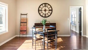 A dining area with a wooden table, chairs, and a wall clock.