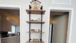A wooden shelf unit with various decorative items and a sign that reads "Home Sweet Home" in a hallway.