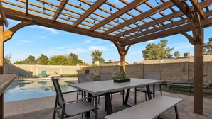 An outdoor patio with a pergola, a pool, and a dining area with chairs and a table. - Heated Pool, Quiet Neighborhood (Phoenix)
