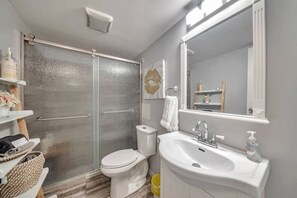Une salle de bain avec douche, toilettes, lavabo et un grand miroir.
