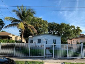 Surrounded by lush greenery, this charming home features a white picket fence and a small porch.