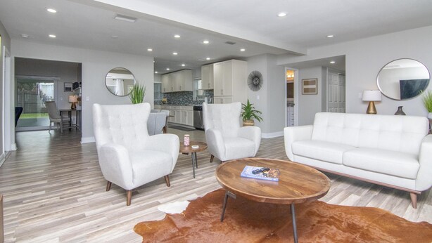 A modern living room with white sofas, a wooden coffee table, and a cowhide rug.