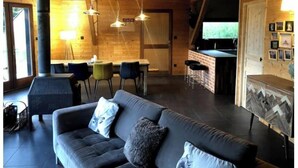 A cozy cabin interior with a sofa, dining area, and a fireplace.