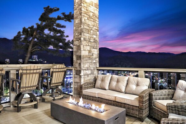 Une terrasse avec mobilier d’extérieur, un pilier en pierre et un foyer.