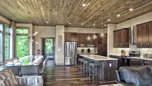 Una cocina moderna con armarios de madera, electrodomésticos de acero inoxidable y una barra con taburetes.