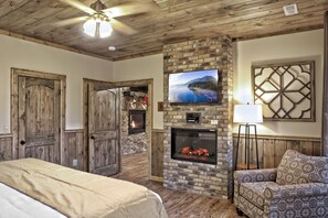 A room with a fireplace, a television mounted on the wall, and a bed. - AMAZING Luxury Cabin! Stunning Views! Fire Pits! Playground! Theater! Game Room! (Gatlinburg)