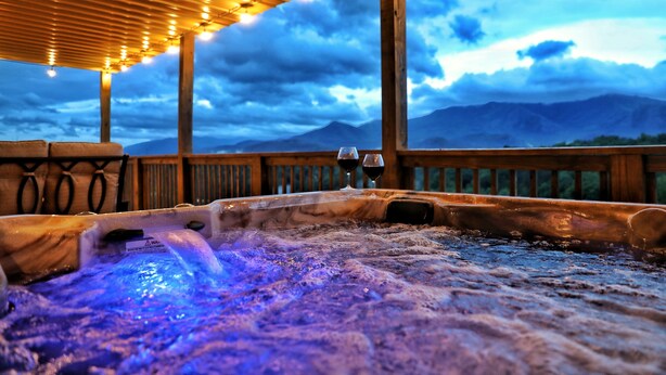 Un bain à remous avec une terrasse en bois et une vue sur les montagnes.