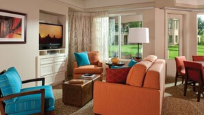Une chambre d’hôtel équipée d’un canapé, de fauteuils, d’une télévision, d’une lampe et offrant une vue sur l’extérieur.