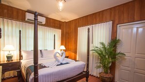 A four-poster bed with a heart-shaped towel arrangement, a potted plant, and a wooden nightstand with a lamp. - Colonial House short walk from Mae Nam beach (Koh Samui)