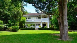 A two-story colonial-style building with a balcony, surrounded by lush greenery and a well-maintained lawn. - Colonial House short walk from Mae Nam beach (Koh Samui)