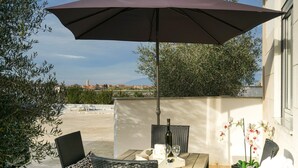 Une terrasse extérieure avec une table et des chaises, un parasol et une vue sur le paysage urbain.