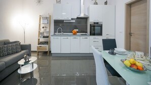 Une cuisine moderne avec des armoires blanches, un four encastré et une hotte de cuisson en acier inoxydable.