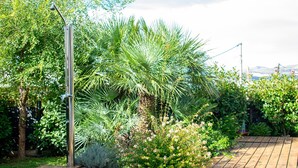 A wooden deck with a metal lamp post and lush greenery including palm trees and flowering bushes. - Villa Grey - Three Bedroom Villa with Swimming pool (Kastel Kambelovac)