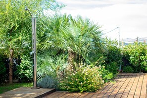 Stroll through the lush garden, surrounded by palm trees and flowering shrubs, along a winding wooden pathway.