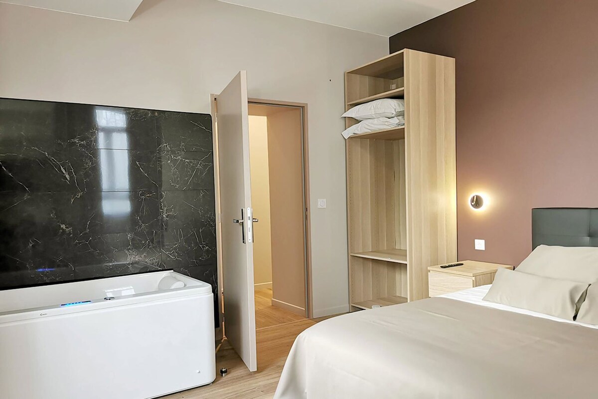 Habitació d'hotel amb un llit, un armari, un televisor i una porta que dóna a un passadís.