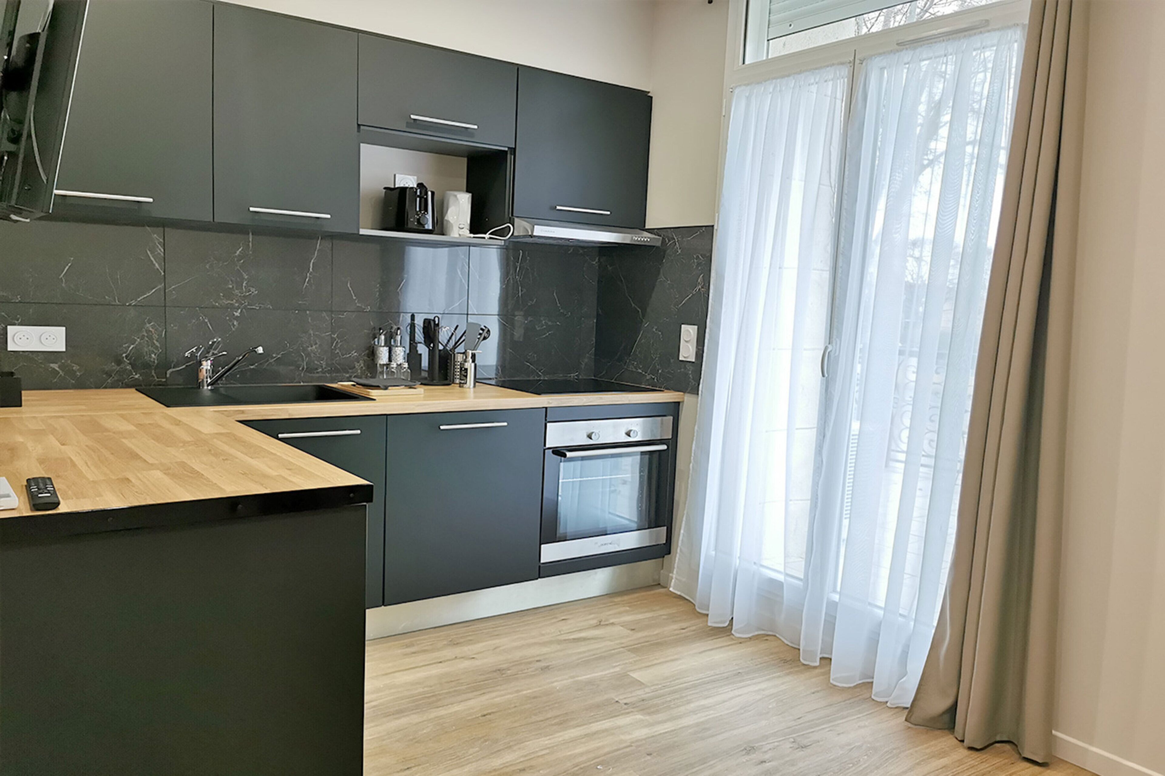 Una cocina moderna con armarios oscuros, encimera de madera y horno empotrado.