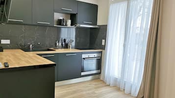 Una cocina moderna con armarios oscuros, encimera de madera y horno empotrado.