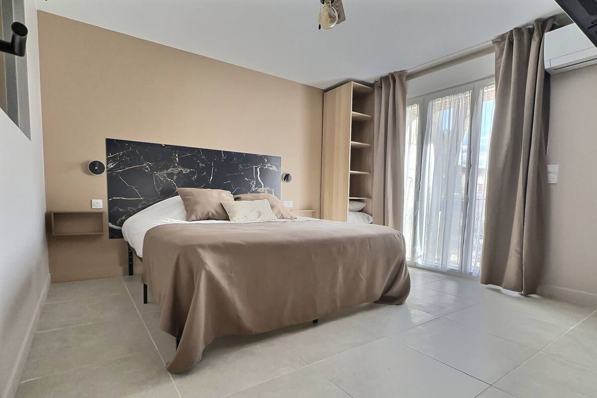 A modern bedroom with a bed, built-in shelves, and a large window with curtains.