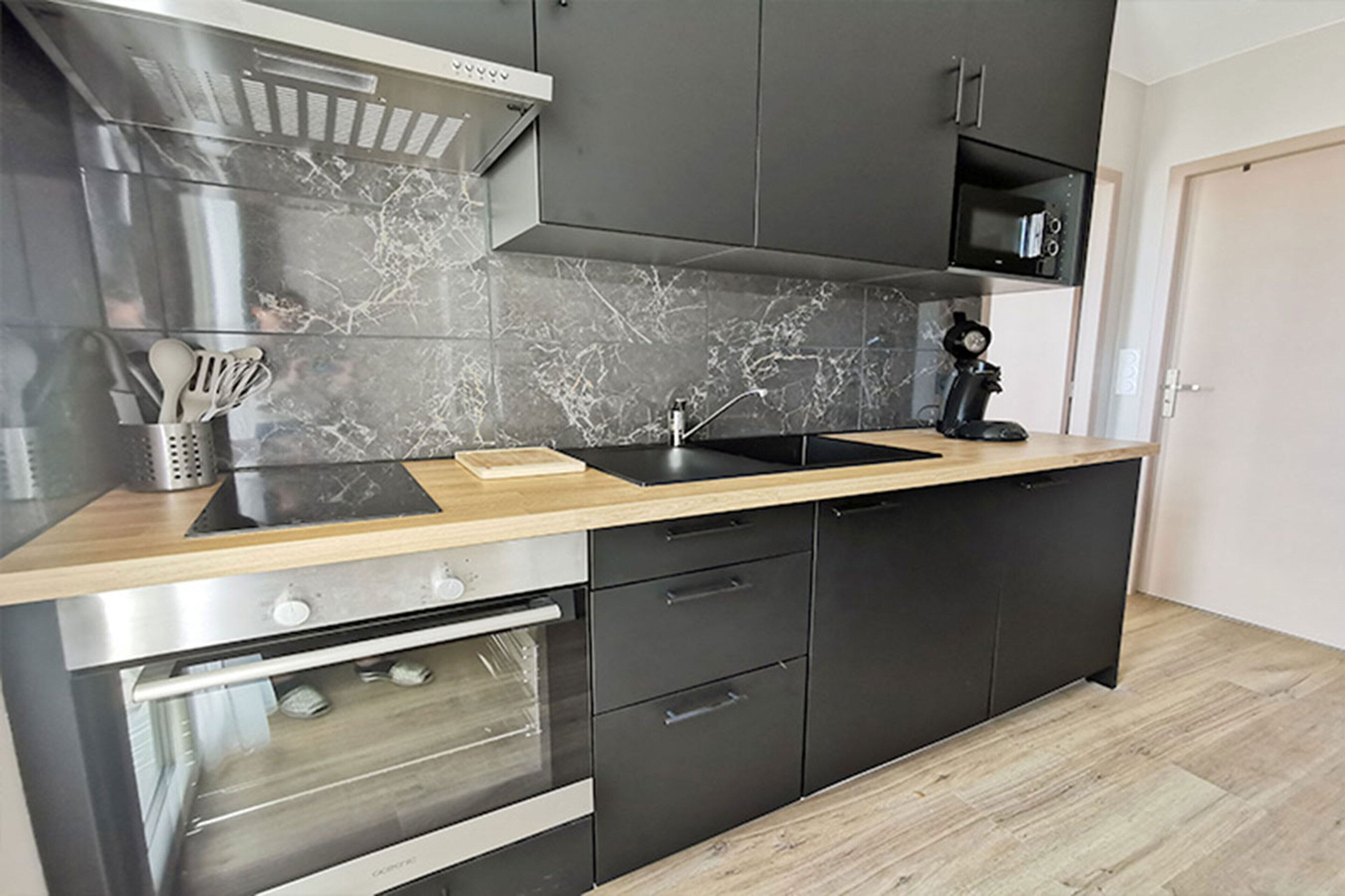 A modern kitchen with a built-in oven, a microwave, and a sink.