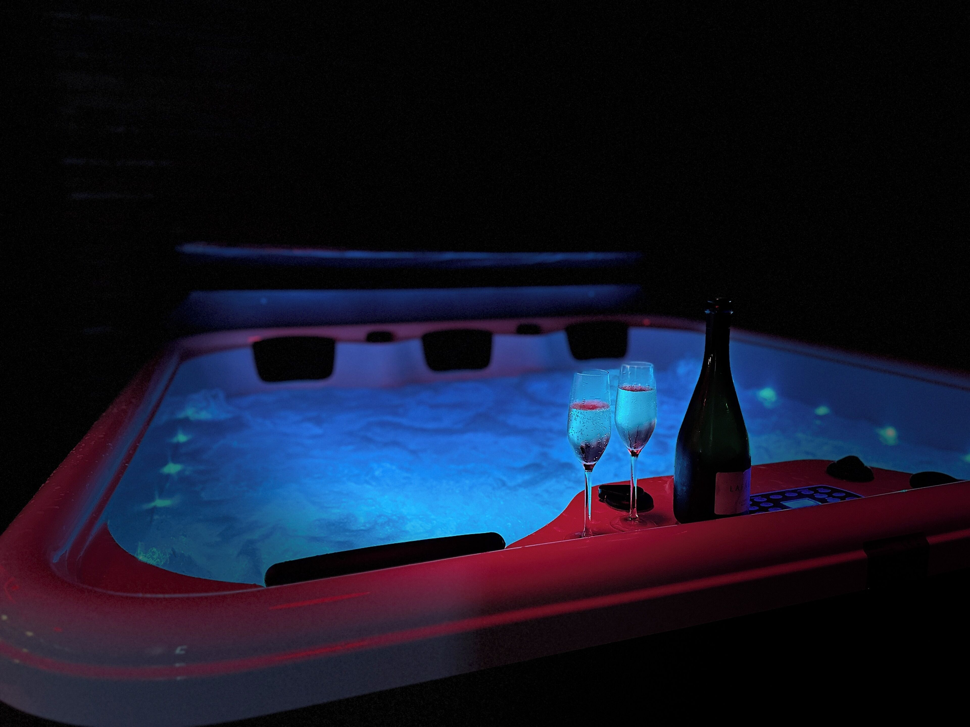 A hot tub with two glasses and a bottle, surrounded by a red frame.