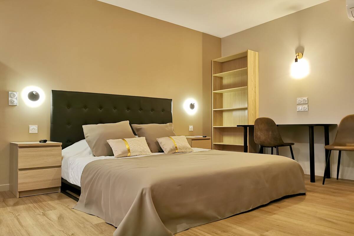 A modern bedroom with a large bed, bedside tables, a desk, and a chair.