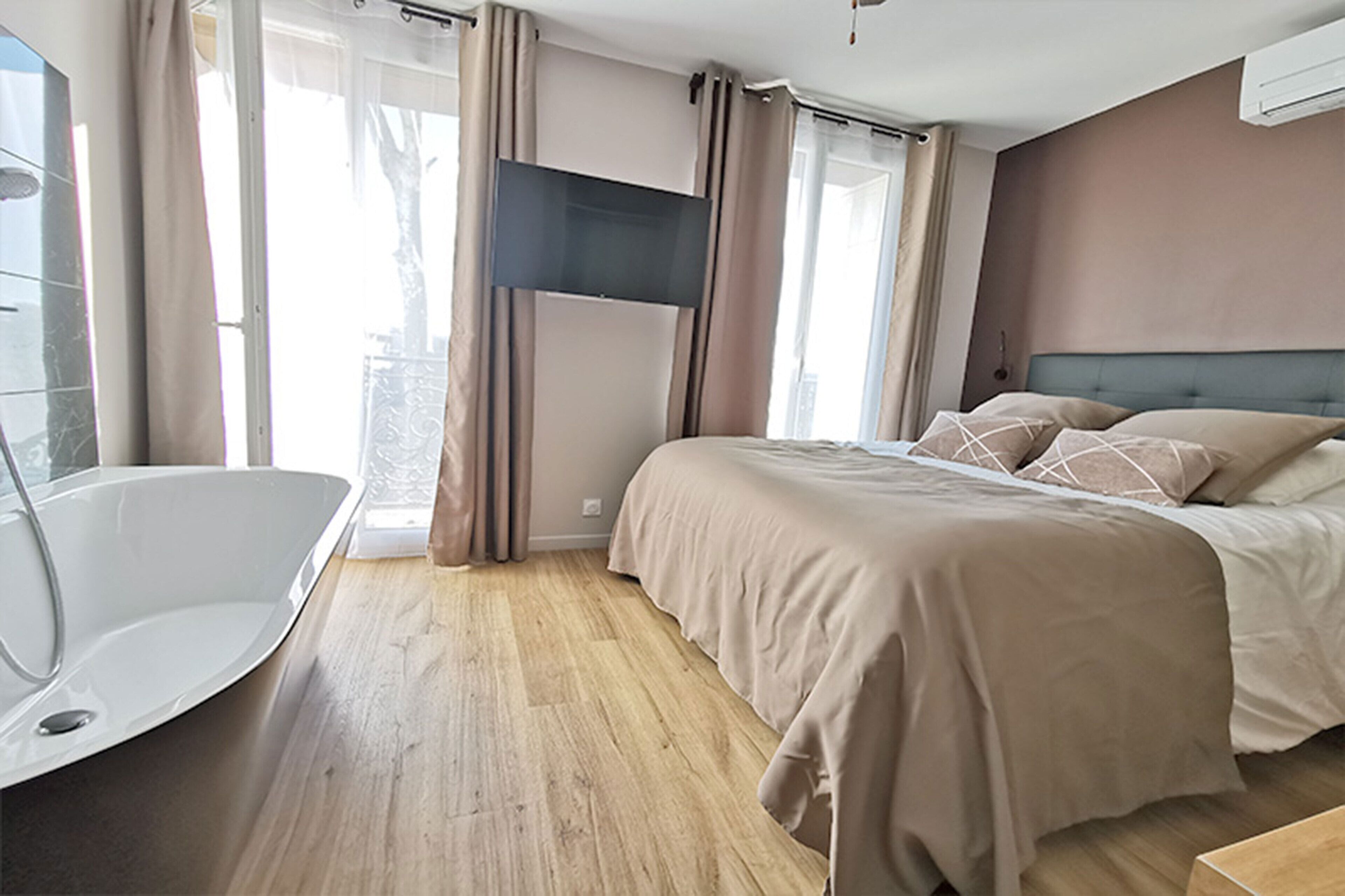 Una habitación de hotel moderna con una cama grande, una bañera y un televisor.