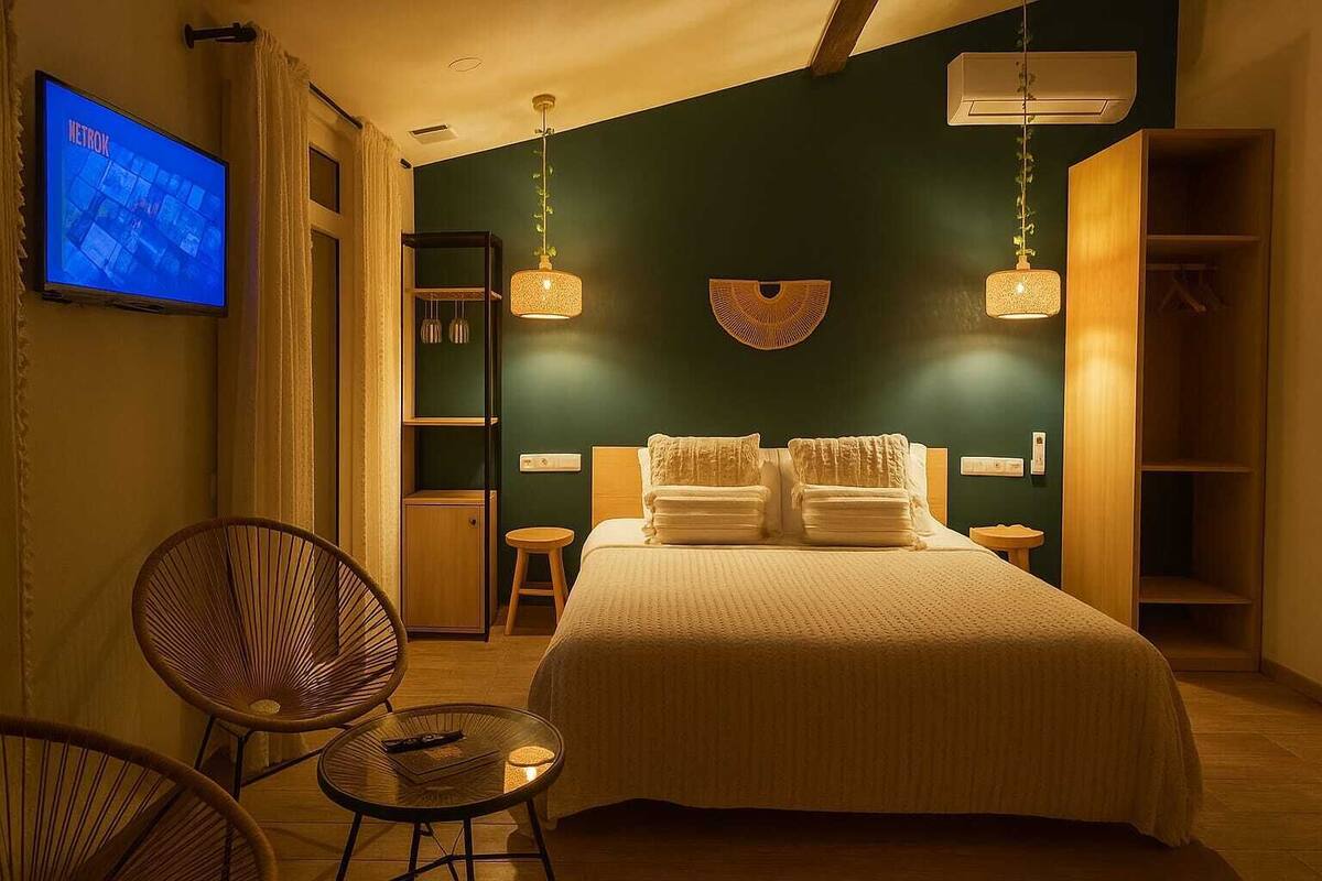 A hotel room with a bed, two bedside tables, a chair, a TV, and a wardrobe.