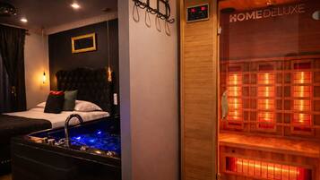 Una habitación de hotel con cama, bañera de hidromasaje y sauna.