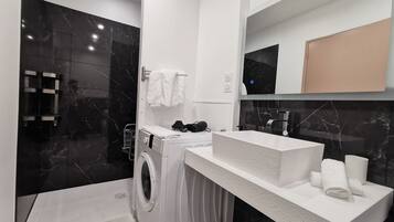 Un baño moderno con lavadora integrada, un espejo grande y un lavabo blanco.