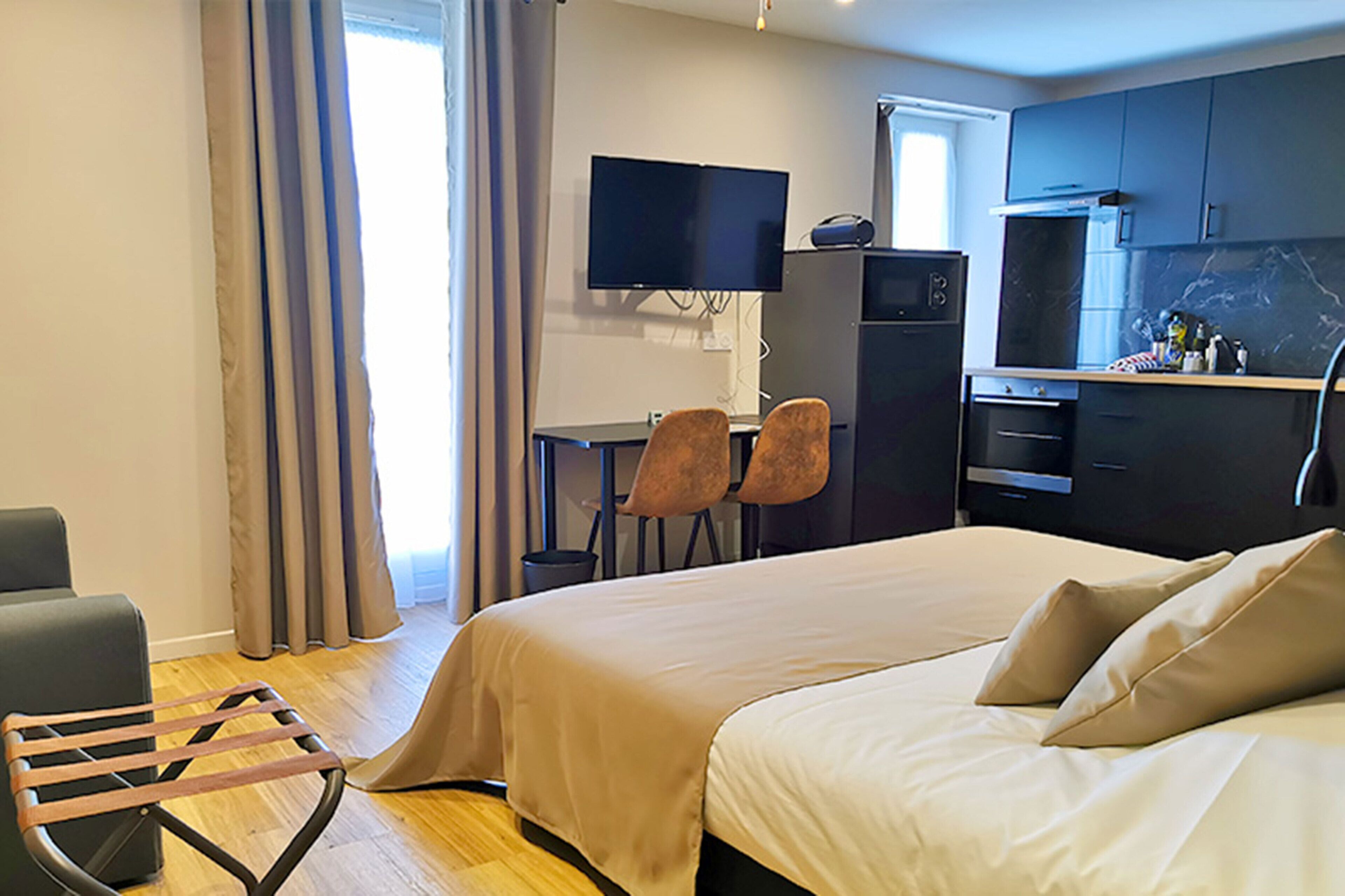 Une chambre d’hôtel équipée d’un lit, d’un bureau, d’une télévision et d’une kitchenette.