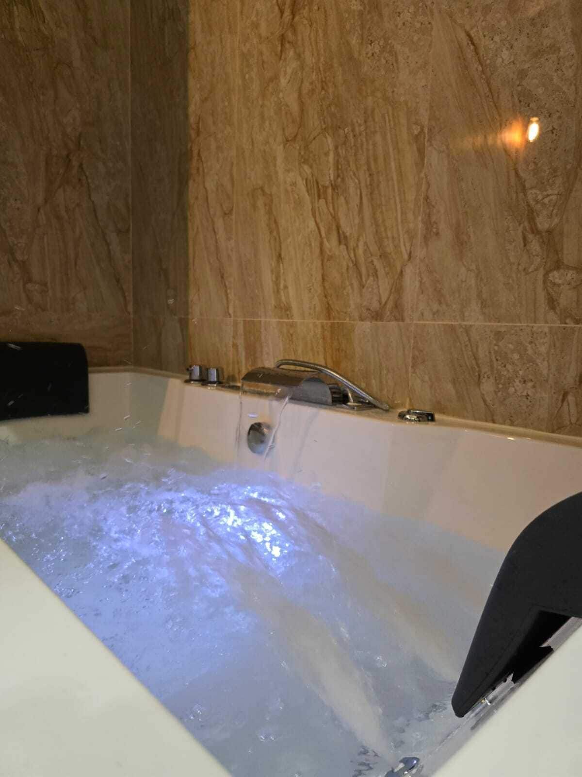 Een bad met stromend water, een douchekop en een bedieningspaneel.